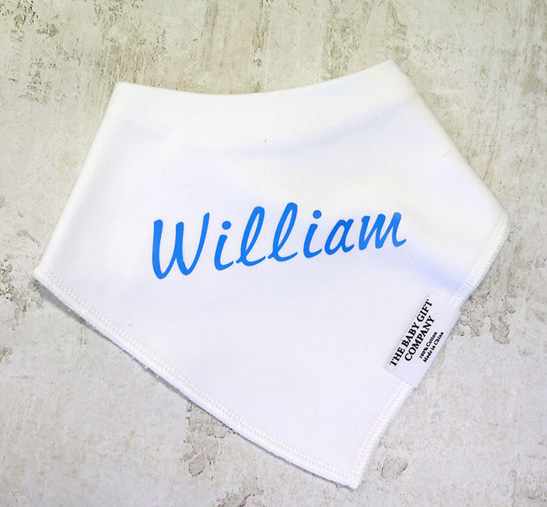 White baby bib with blue text 'William' on a textured surface