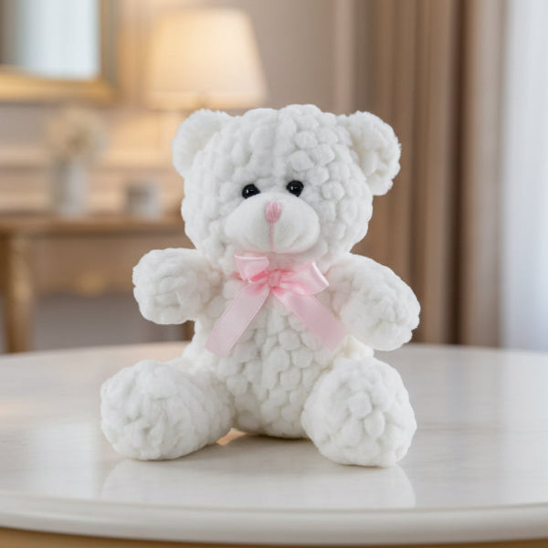 White teddy bear with a pink bow on a table