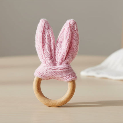 Pink knitted bunny ear teething ring on a white background
