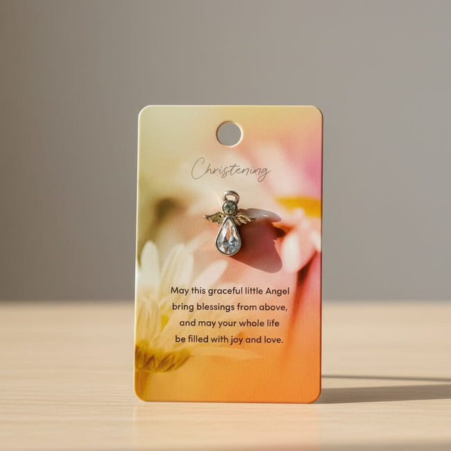 Card holding an angel pin for christening on a table