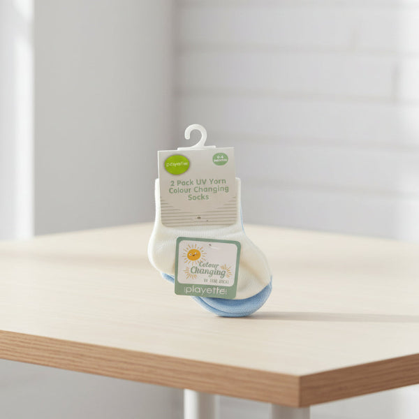 Two pairs of baby socks with UV yarn, displayed against a table background.