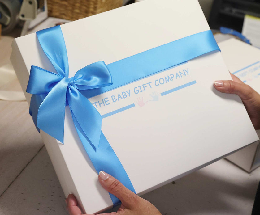 White gift box with blue ribbon and 'The Baby Gift Company' text