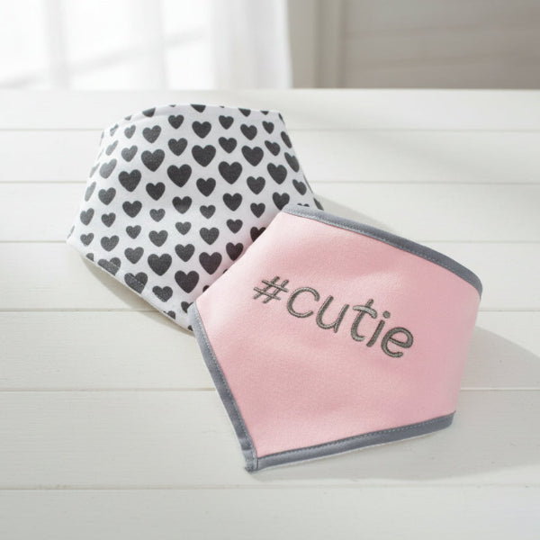 Two baby bibs, one with heart pattern and the other pink with '#cutie' text.