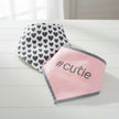 Two baby bibs, one with heart pattern and the other pink with '#cutie' text.