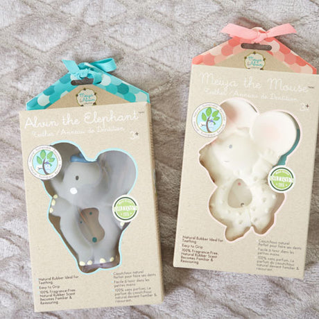 Two elephant-shaped toys in their packaging on a textured surface
