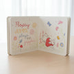 Open hello flopsy book with illustrations of a bunny and flowers on a table background