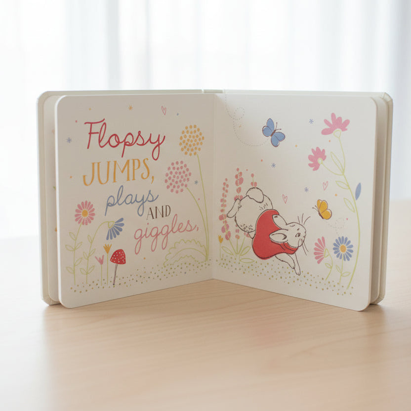 Open hello flopsy book with illustrations of a bunny and flowers on a table background