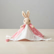 Plush flopsy rabbit toy on a pink blanket with a table background