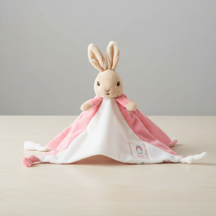 Plush flopsy rabbit toy on a pink blanket with a table background