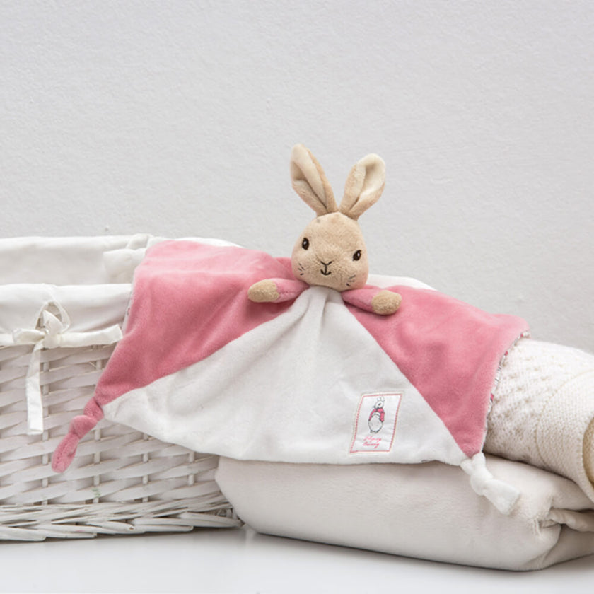 Plush rabbit toy with pink blanket on a white background
