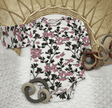 Floral-patterned baby onesie on a textured surface with rattan basket and wooden toys.