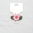 Pink flower hair clip on a white card with a textured white background