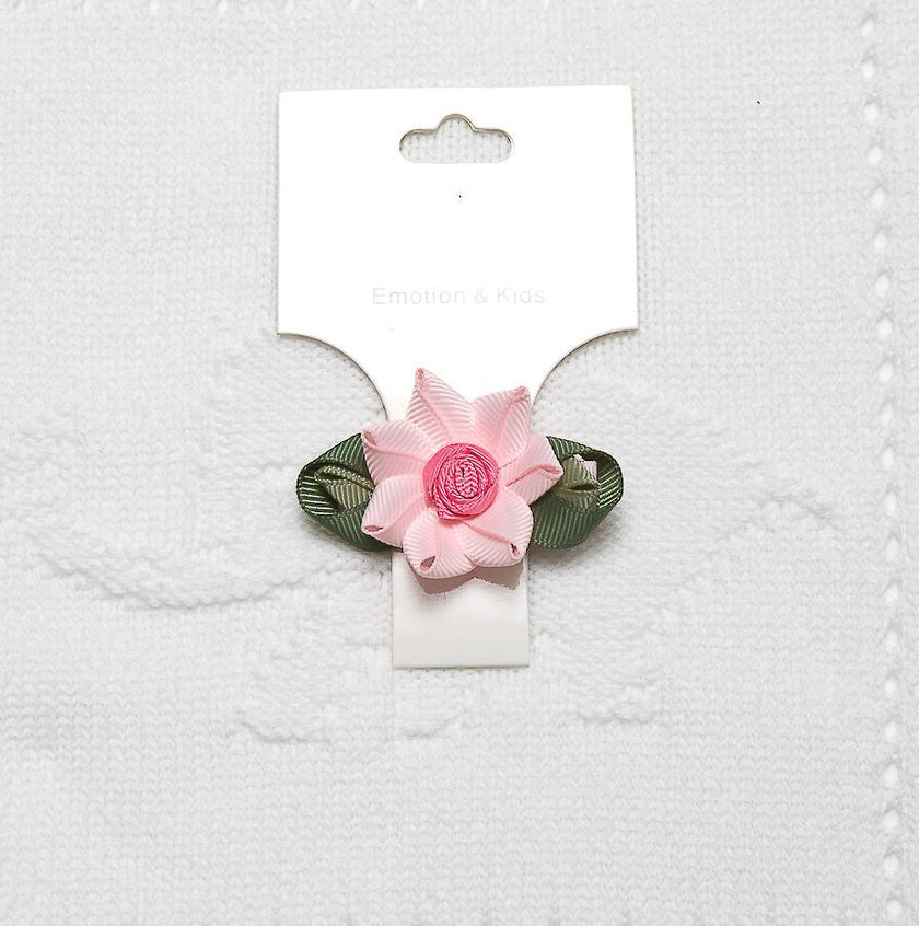 Pink flower hair clip on a white card with a textured white background