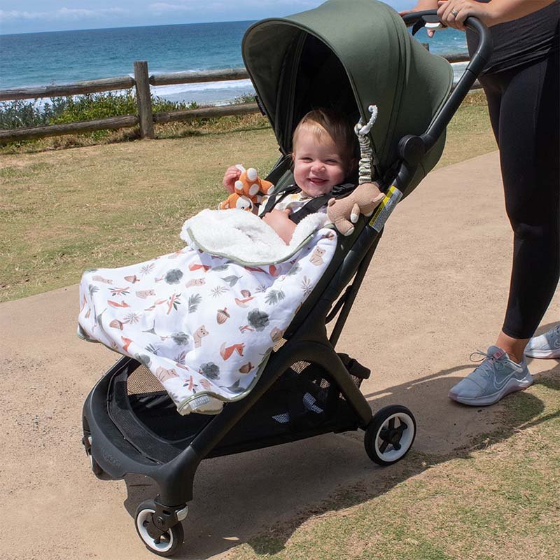 baby in pram with green forest animal blanket