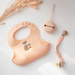 Blush Silicone Bib with fox design and other baby items on white table