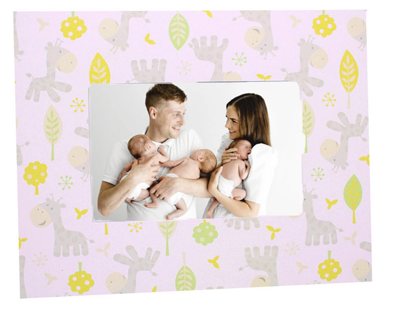 Family holding two babies with a decorative frame featuring animal patterns on a pink background