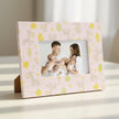 Family holding two babies with a decorative frame featuring animal patterns on a table background