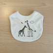 white baby bib with two giraffe printed on wooden table