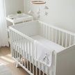 white baby blanket with two giraffes printed in baby cot