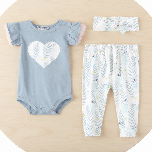 Baby outfit set with blue onesie, white pants, and headband on a table background