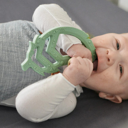 baby holding green teether toy