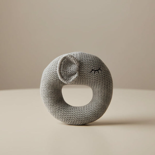 Gray knitted rattle toy on a table background