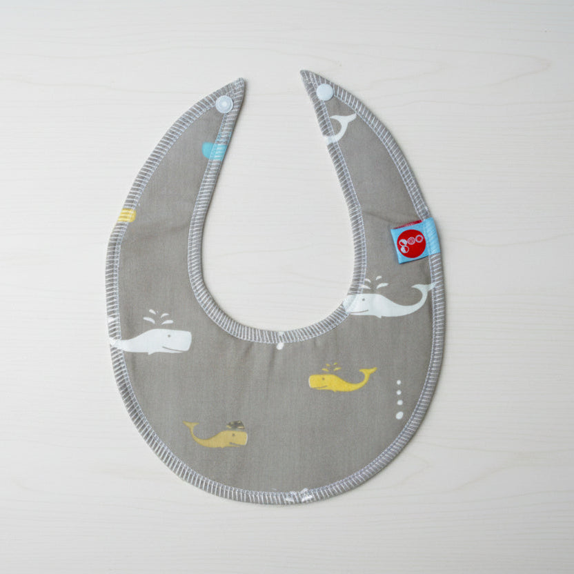Grey bib with whale patterns on a table background