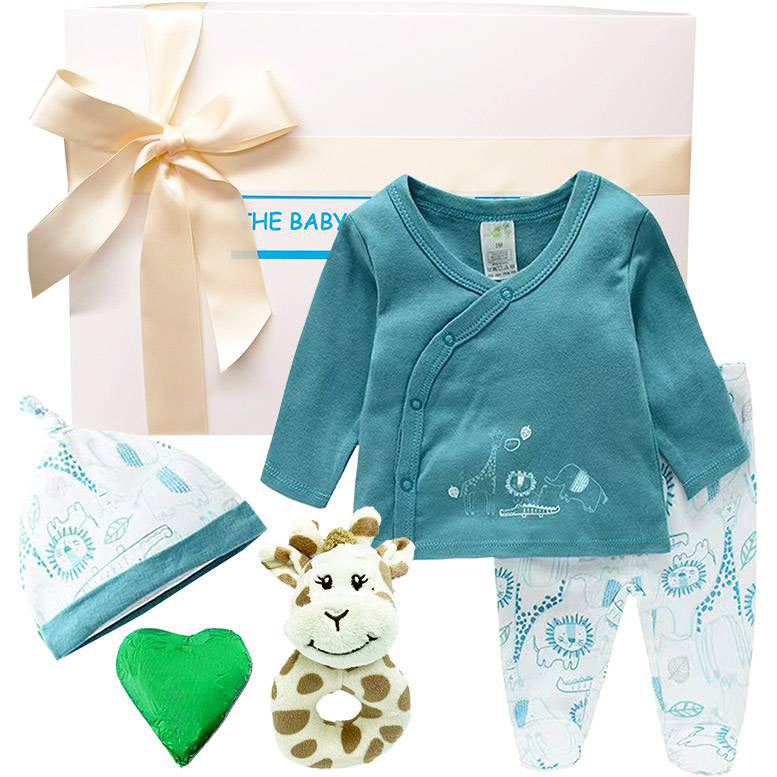 Baby clothing set with teal cardigan, white pants, hat, and rattle in front of a gift box.