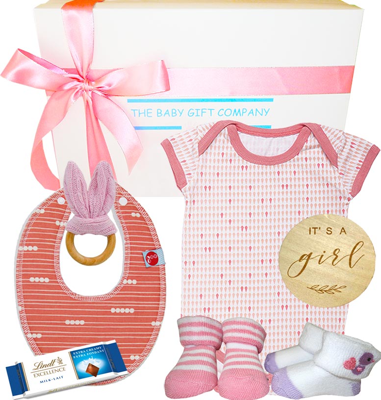 Baby gift set with pink baby clothes, teether, bib, socks, and Lindt chocolate bar from The Baby Gift Company.