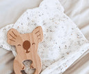 Wooden koala-shaped teether on a soft fabric background