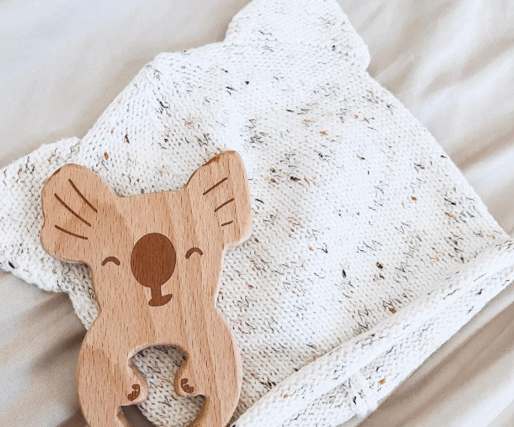 Wooden koala-shaped teether on a soft fabric background