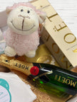 Small plush sheep toy on top of a bottle of Moët & Chandon champagne with a blurred background.