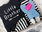 Black 'Little Brother' onesie with a gray stuffed animal on a marble surface