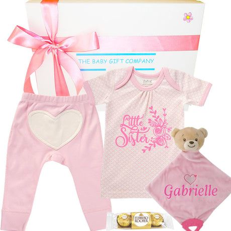 Baby gift set with pink baby onesie, pants, and teddy bear with 'Little Sister' text.