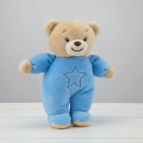 Plush teddy bear in a blue onesie with a star on a table background