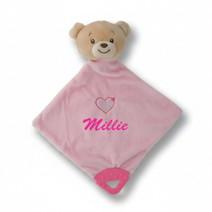 Pink plush blanket with a teddy bear face and heart design on a white background