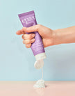 Hand holding a tube of Epzer body lotion against a light blue background