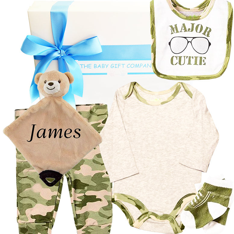 Baby gift set with teddy bear, bib, and clothing items in a gift box on a white background