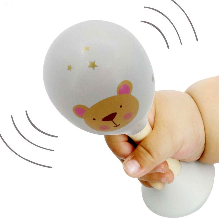 Baby rattle with bear design held by a hand on a white background