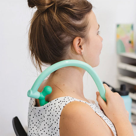 Person wearing a white polka dot top with a green neck support device.