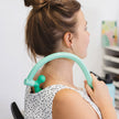 Person wearing a white polka dot top with a green neck support device.