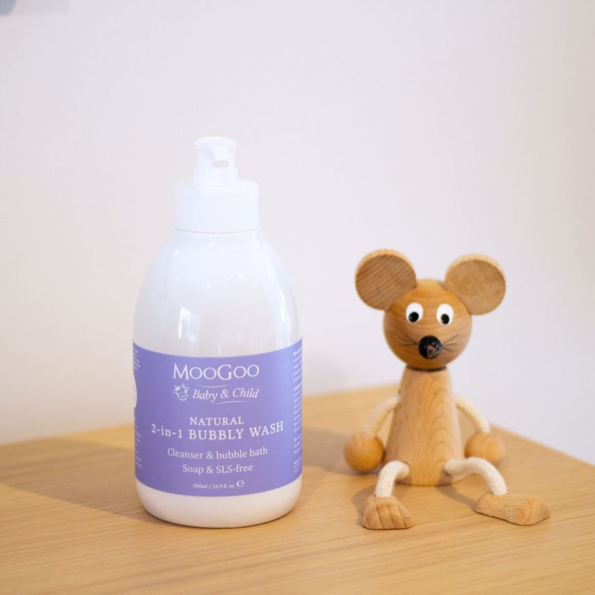 MooGoo natural 2-in-1 bubbly wash bottle with a wooden toy mouse on a wooden surface.