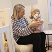 Mum holding baby with Giraffe Doudou toy