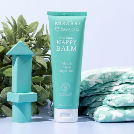 MooGoo Natural Nappy Balm with baby wipes and a toy on a light blue background