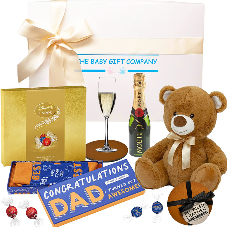 Collection of gifts including a teddy bear, chocolate, champagne, and Lindt chocolate box from The baby gift company