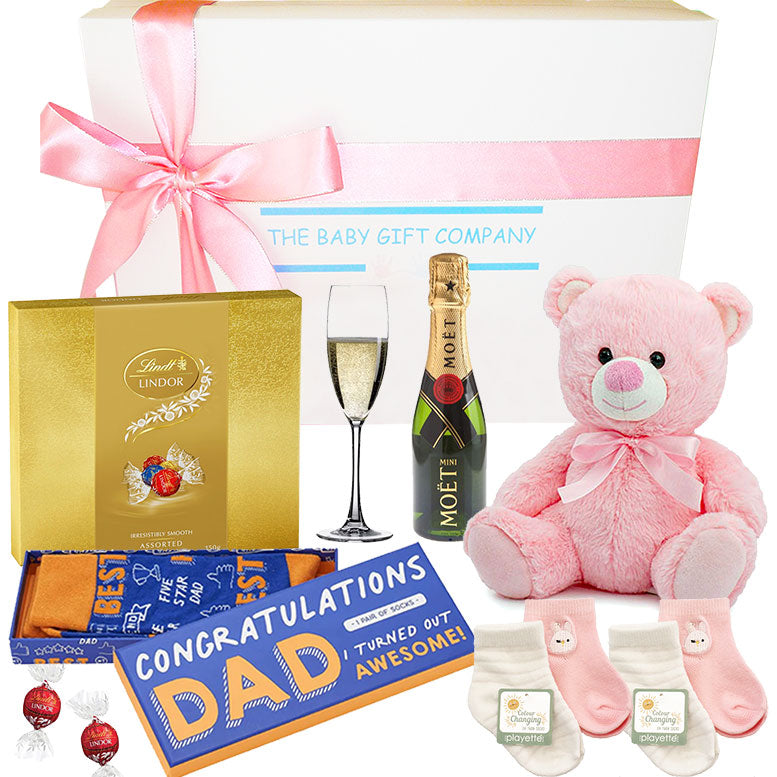 Gift set with pink teddy bear, Lindt chocolate, Moet champagne, and baby socks with 'Congratulations Dad' socks.