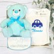 Baby gift box with blue teddy bear, bib, and bodysuit with car design, branded 'The Baby Gift Company'.