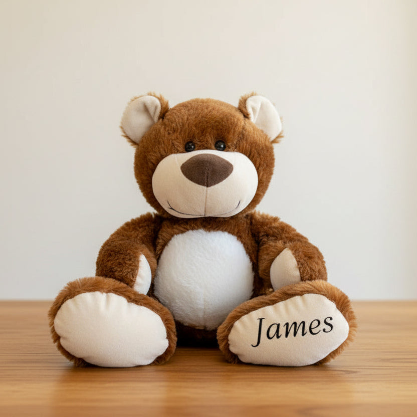 Brown teddy bear with 'James' on a wooden table background
