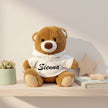 Personalised brown hoodie teddy bear with custom baby name sitting on a shelf