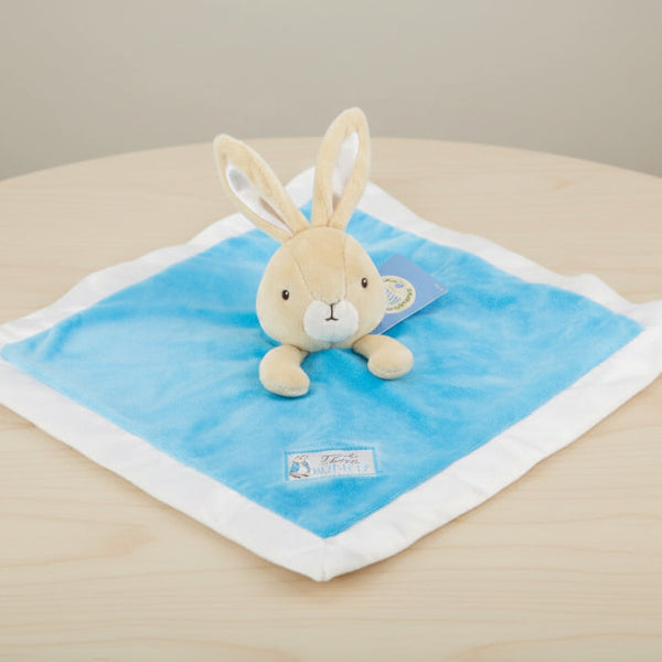 Plush toy rabbit on a blue blanket with a white border on table